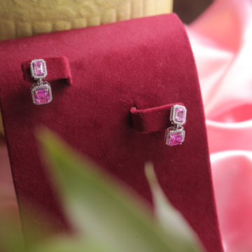 A close-up of Dark Pink Sterling Silver Statement Earrings, glowing with elegance.
